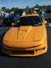 1996 Ford Probe - A bright orange sports coupe with a distinctive hood scoop is the focus of this photo, with other vehicles and people in the background.
