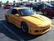 1996 Ford Probe - A modified yellow sports car is parked in a lot with other vehicles.