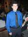 1996 Ford Probe - A man wearing a blue dress shirt, black tie, and fedora poses for a photo in a busy indoor venue.