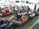 1996 Ford Probe - Several go-karts are parked in a line at an outdoor track, with people seated in some of them.