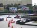 1996 Ford Probe - Go-karts race around a track with advertising billboards visible.