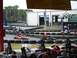 1996 Ford Probe - Go-karts race around a track, with spectators and a building visible in the background.