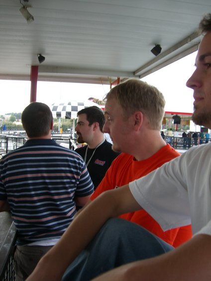 People gathered under a covered area with a checkered umbrella in the background