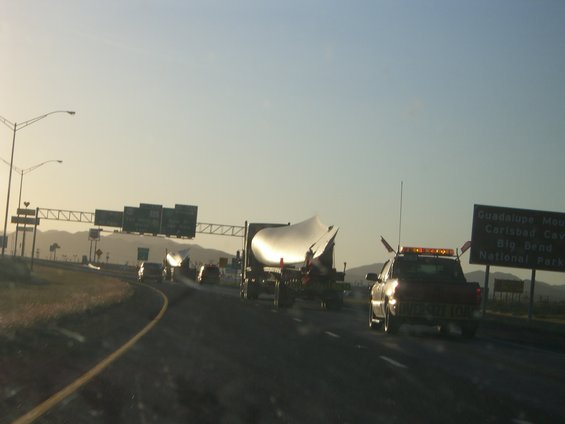 Oversized load on flatbed truck with escort vehicle on highway