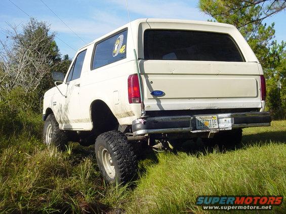 White Ford Bronco with lifted suspension and off-road tires parked in grassy field