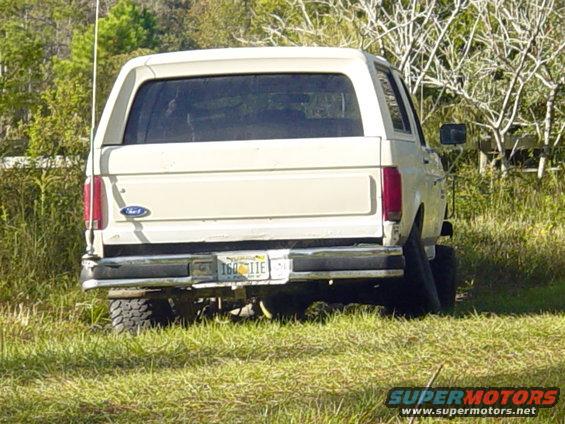 Rear view of a beige Ford Bronco parked in grass. License plate reads 160 IIE