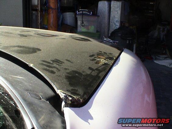 Carbon fiber car hood with water stains and damage at the edge
