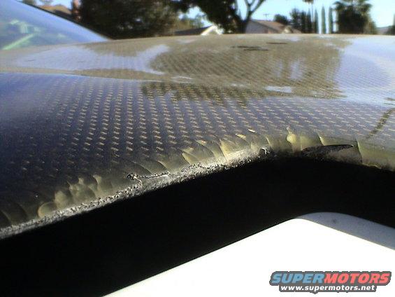 Close-up of damaged carbon fiber hood with peeling edges