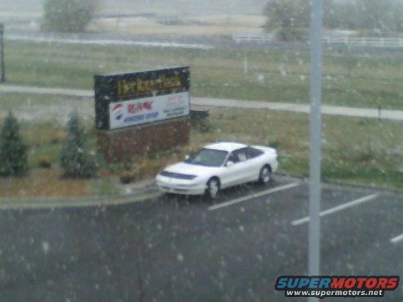 White coupe parked outside a building with a sign that says Heritage Bank and RE/MAX