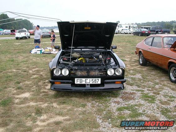 Black Capri with hood open, showing engine. Another Capri is parked to the right. License plate FB-EJ 587