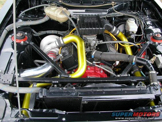 Engine bay with turbocharger, yellow intake piping, and red engine block