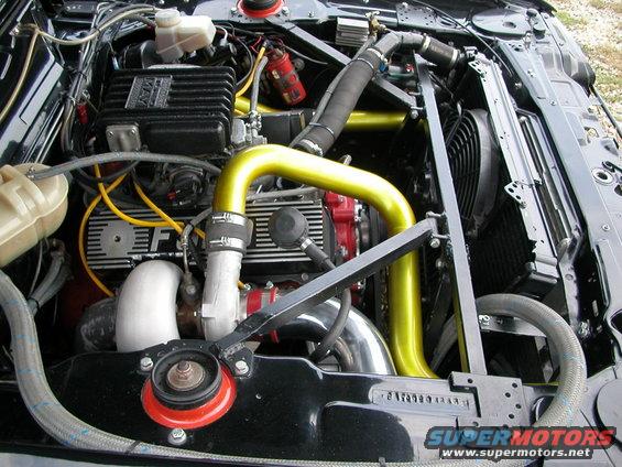 Engine bay with yellow intake pipes, black valve covers, and a turbocharger