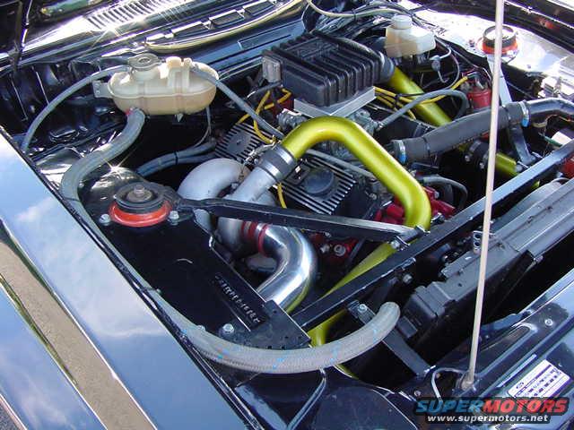 Engine bay with yellow intake tubes, black radiator, and a coolant reservoir