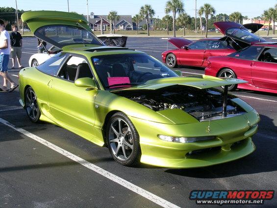 Lime green Ford Probe with hood and trunk open, parked next to red cars