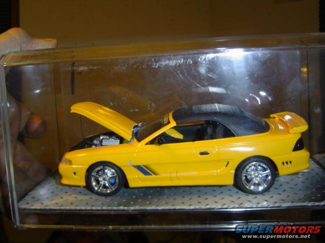 Yellow convertible model car with hood open, showing engine detail