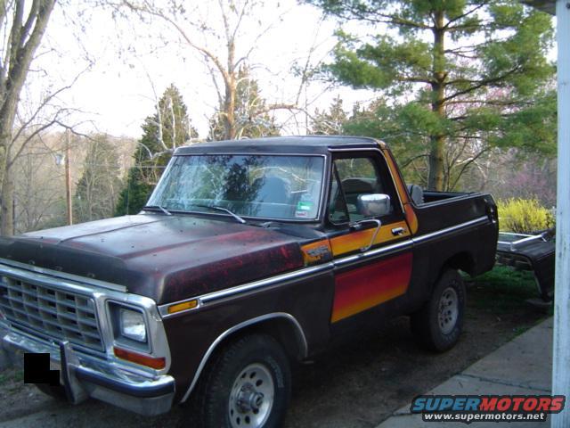 Dark red 1978 Ford Bronco with orange and yellow stripe, parked outdoors