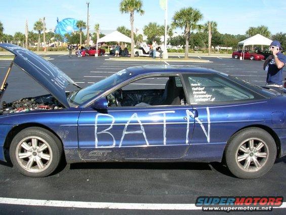 Blue 1993 Ford Probe coupe with white lettering "BATIN" on the side, hood open, parked in a lot