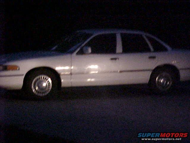 White 1993 Ford Crown Victoria sedan, side view, showing front wheel and door handles