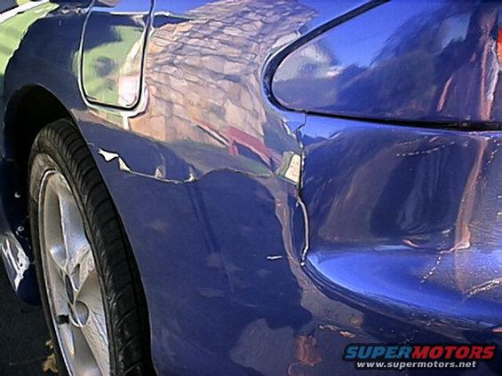 Blue car's rear quarter panel showing damage and peeling paint near the wheel well