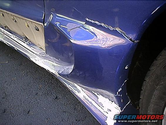 Blue car side panel with significant damage and peeling paint