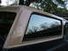 1988 Ford Bronco - The rear side window and tan top of a Ford Bronco are shown, with reflections of trees in the glass.