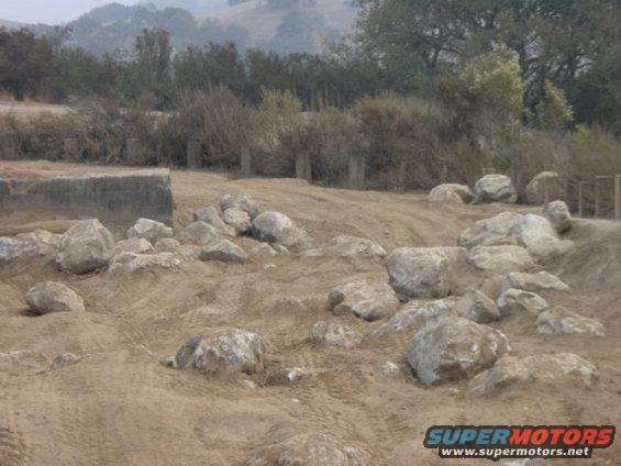 Off-road terrain with large rocks and tire tracks