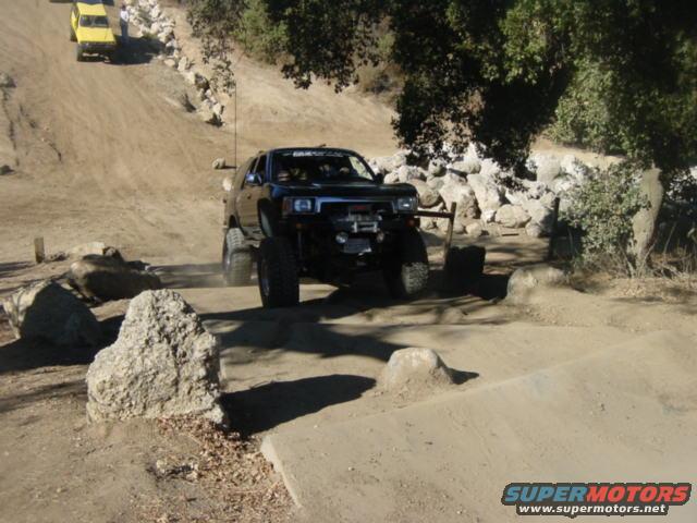Black off-road SUV with lifted suspension driving on a dirt track