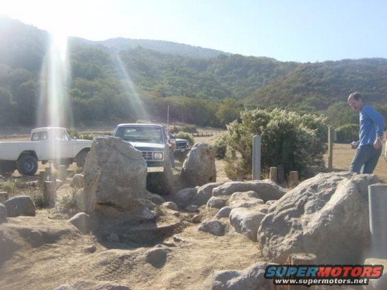 1986 Ford Bronco II and a white pickup truck navigating a rocky trail