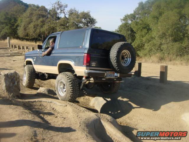 Blue 1986 Ford Bronco II off-roading over rocks and dirt