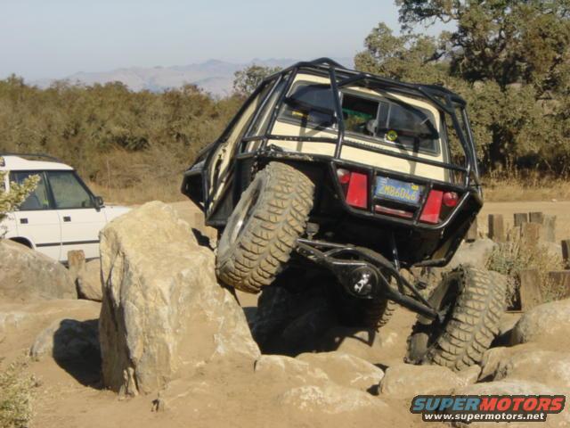 Modified off-road vehicle with roll cage on rocks, rear view. California license plate ZMB6046