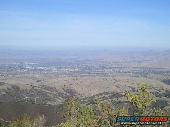 Vista of a valley and distant city with Supermotors logo