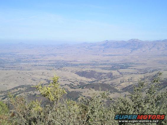 View of a valley with a town and mountains under a clear blue sky