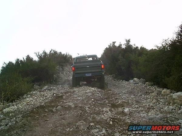 Rear view of a 1986 Ford Bronco II driving on a rocky trail