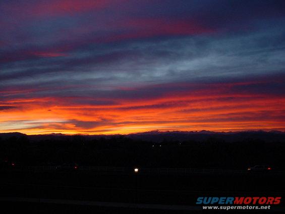 Sunset over mountains with a highway and a distant car
