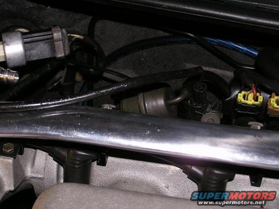 Close-up of engine bay parts including fuel injectors and wiring