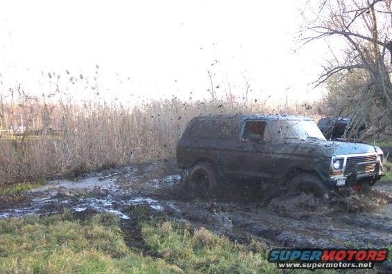 Muddy SUV stuck in a bog, another vehicle visible behind it