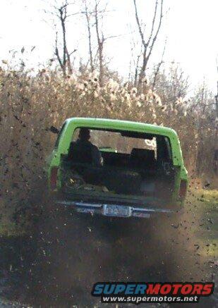 Green SUV rear view, kicking up mud