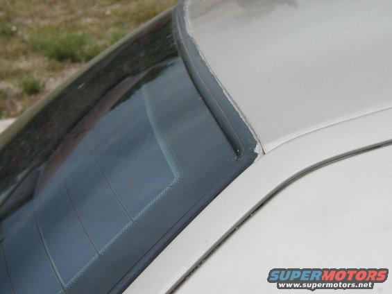 White car's rear window seal is peeling away from the glass