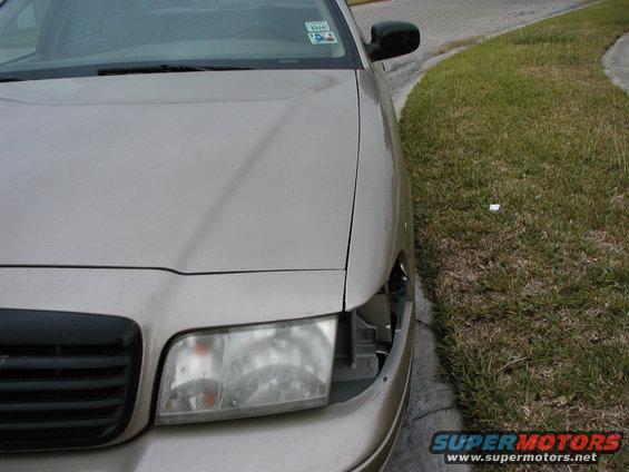 Tan sedan with missing headlight assembly and black grille