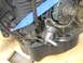1993 Mazda MX-3 - Engine part with a blue strap secured to it, focus on mechanical details.