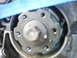 1993 Mazda MX-3 - A close-up view of a mechanical engine component, possibly a timing pulley or gear, with visible bolts and a central hex nut.
