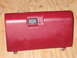 1994 Ford Bronco - A red glove box door is shown against a wooden background, with a black latch and a visible screw hole.
