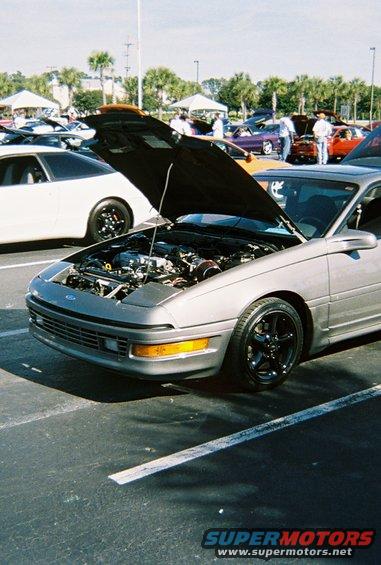 Silver 1991 Ford Probe with hood open, showing engine. Black rims, slight damage on front bumper
