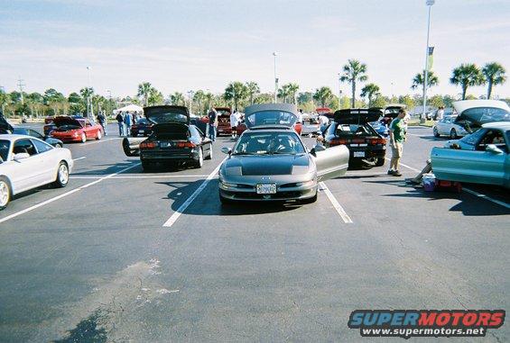 Several Ford Probe cars parked in a lot, some with hoods and doors open. The front car is gray