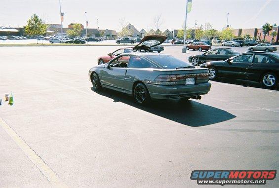 Gray coupe with black rims and a spoiler, parked in a lot. License plate is visible