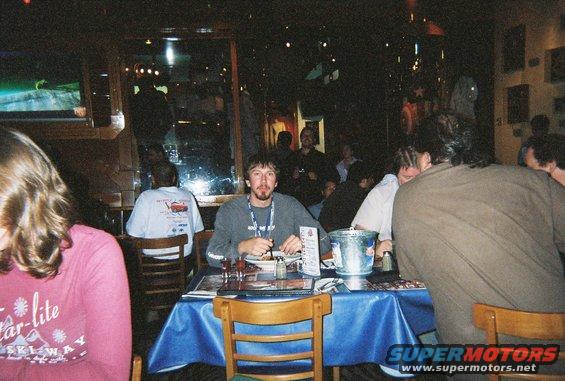 People sitting at tables in a dimly lit restaurant, some eating