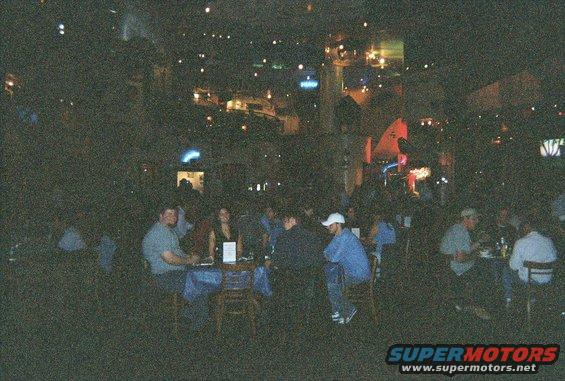 People seated at tables in a dimly lit restaurant with lights in the background