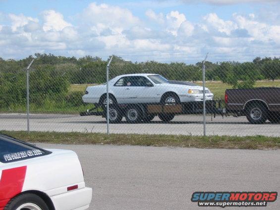 White 1990s coupe on trailer, side view