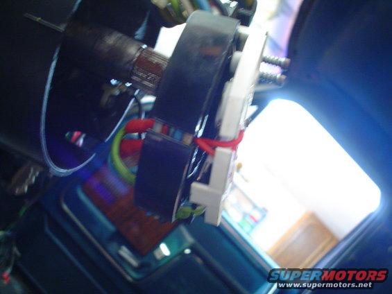 Close-up of steering column wiring harness with red zip tie and circuit board