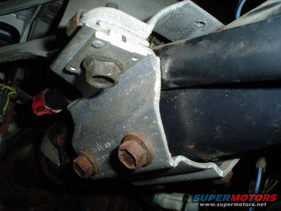 Close-up of a metal bracket attached to a black tube, with bolts and wiring visible